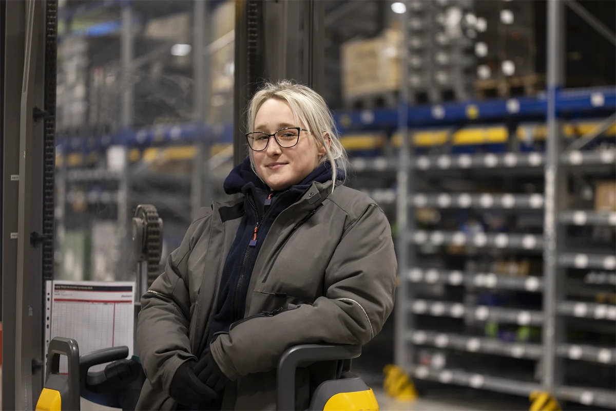 Ung kvinnlig truckförare på ett lager