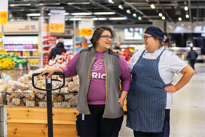 Ett samtal mellan två glada kvinnor som jobbar i matbutik.